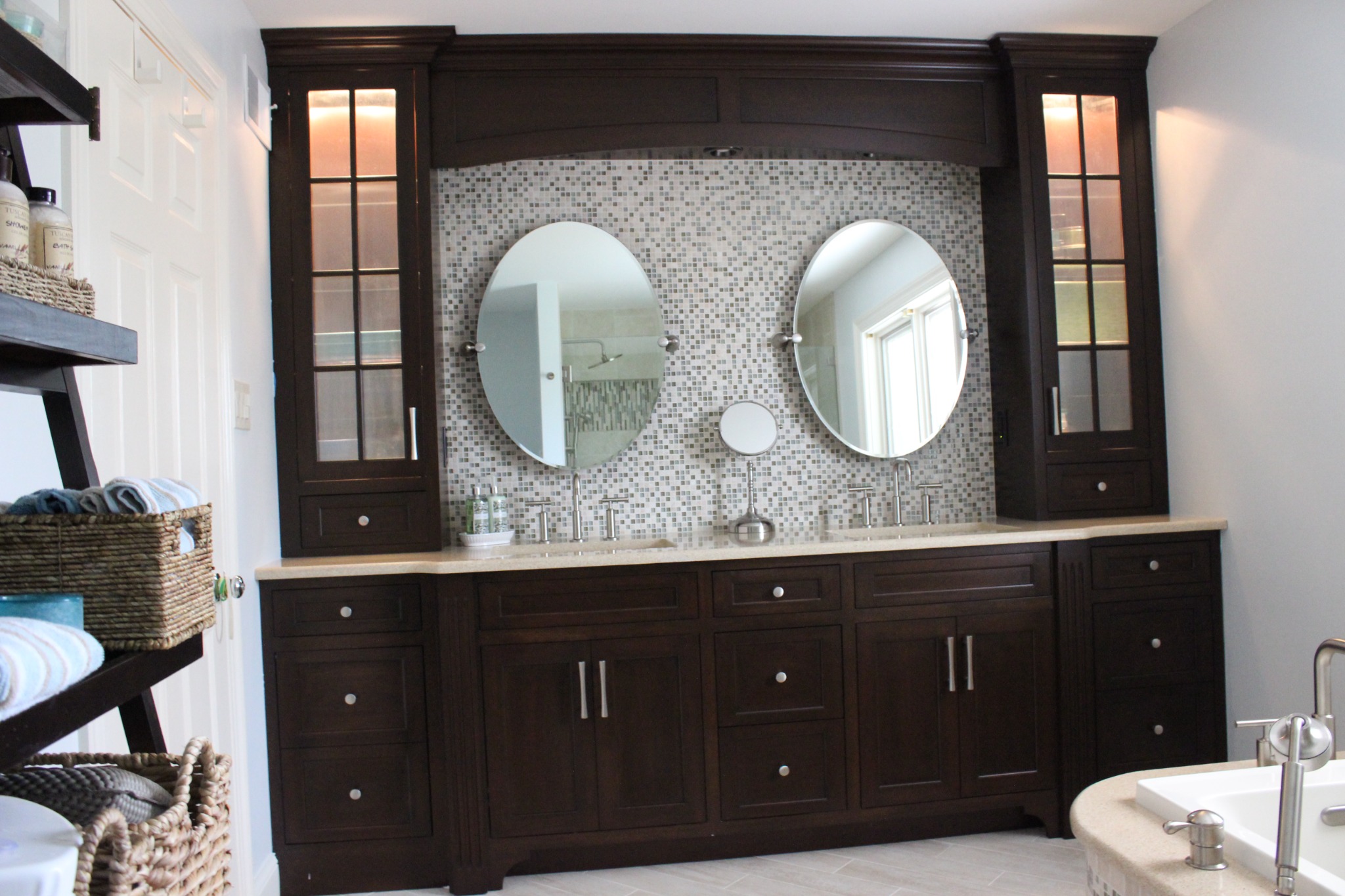 Custom dark bathroom vanity with tall glass-front cabinets