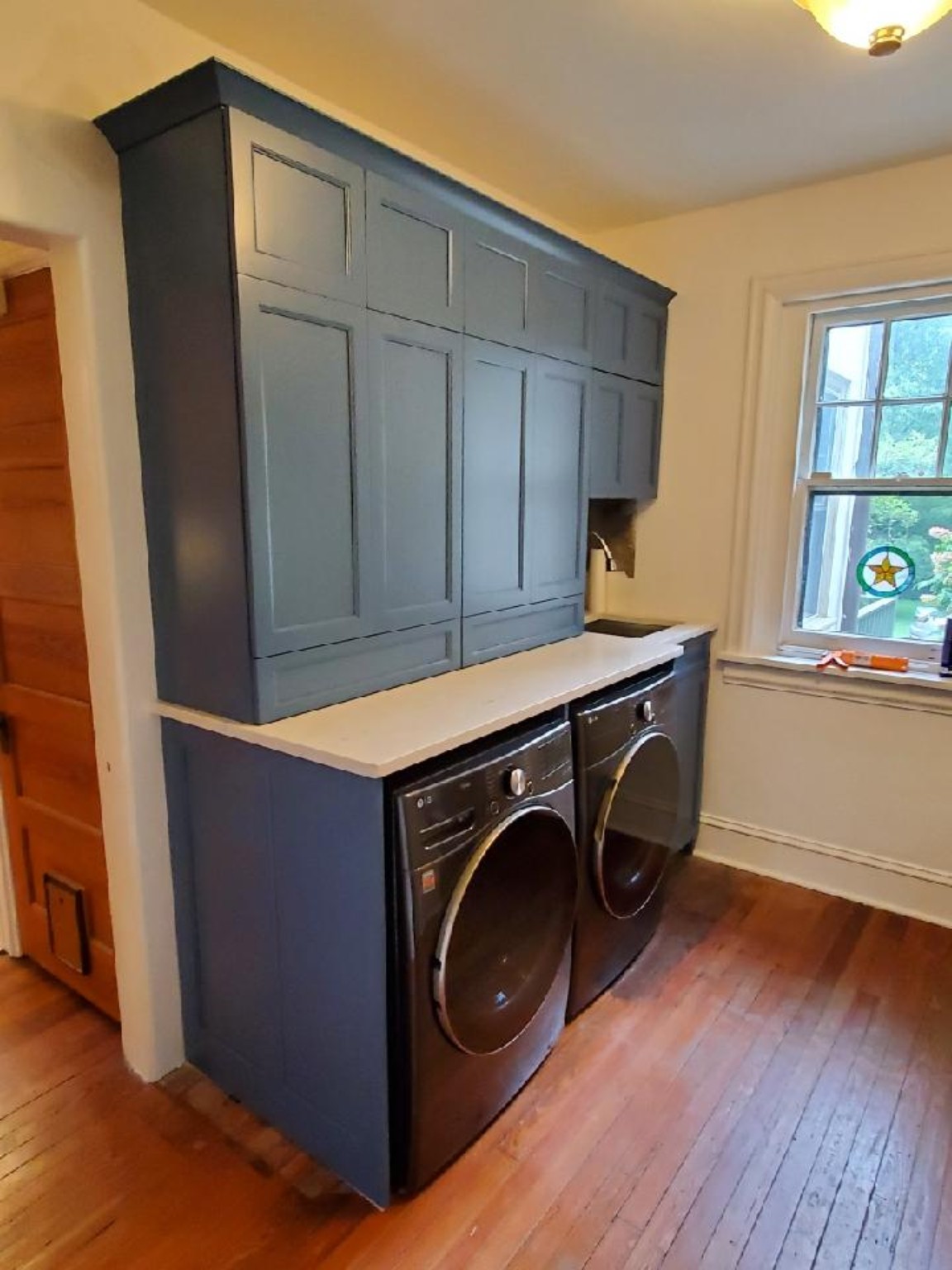 Custom blue painted laundry room cabinetry with fitted storage above and beside the machines