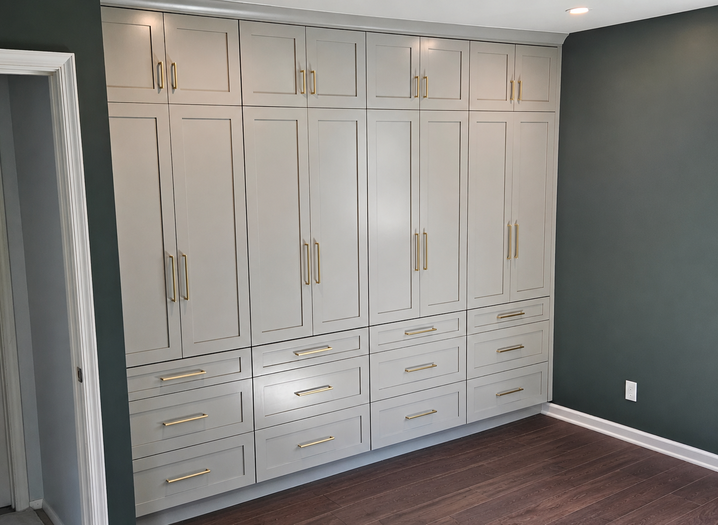 Gray full-wall custom wardrobe and closet cabinetry with brass hardware and fitted interiors