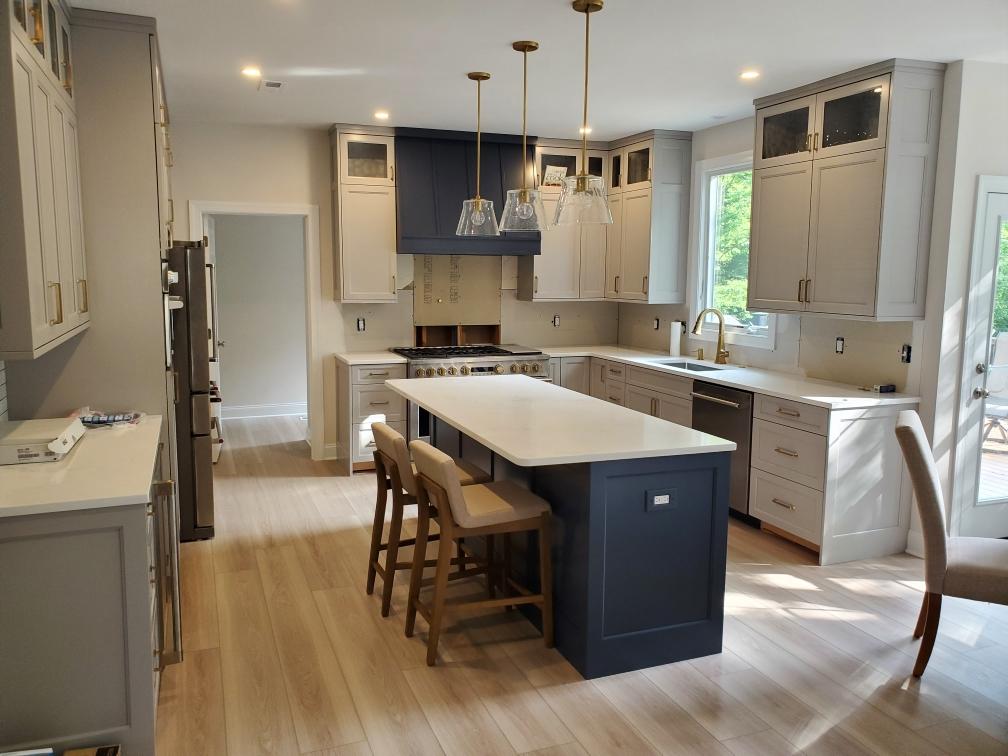 Alternate view of the white painted kitchen showing the blue island, range wall and glass upper cabinetry